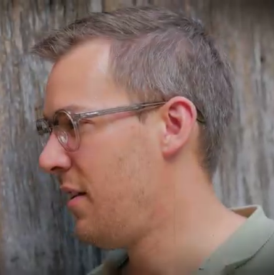 Profilansicht eines Mannes mit Brille und kurzem, hellbraunem Haar.