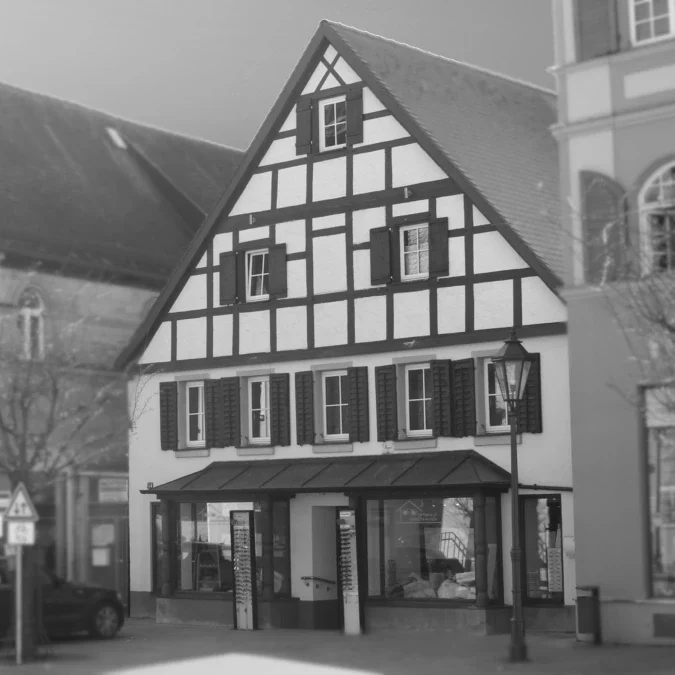 Optikhaus Gunzenhausen von Außenansicht Traditionelles Fachwerkhaus mit schwarzer und weißer Fassade und Fensterläden.
