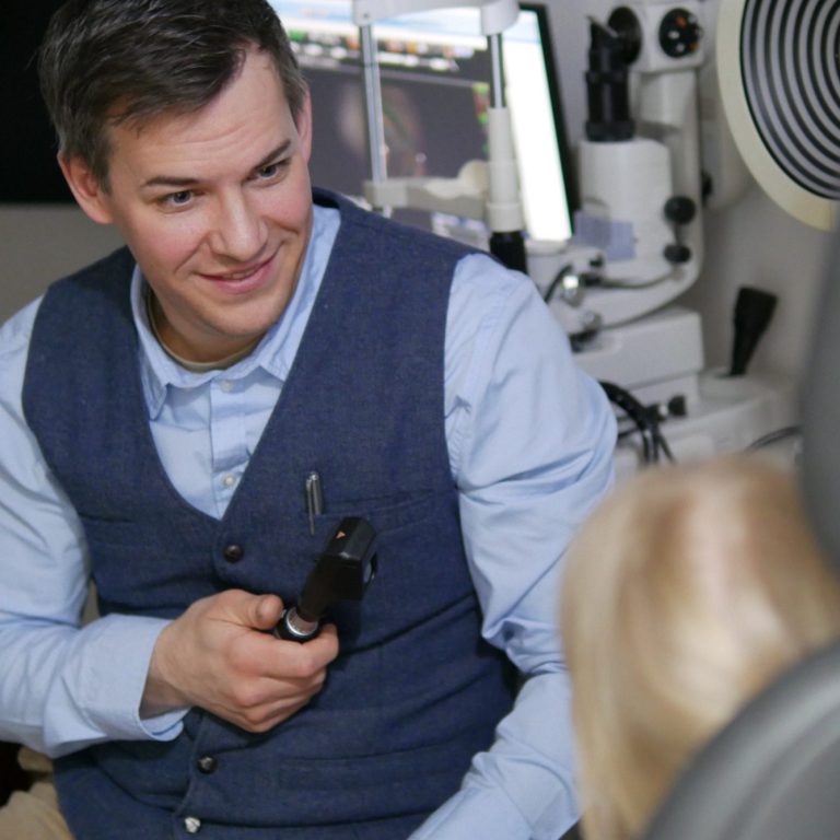 Ein Optiker untersucht ein Kind mit einem Skiaskop.